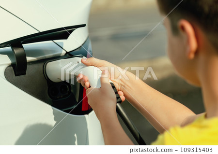 Hand insert EV charger plug into electric vehicle to recharge EV car. Perpetual Hand insert EV charger plug into electric vehicle to recharge EV car. Perpetual 109315403
