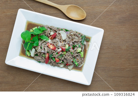top view of homemade style spicy minced beef salad in a plate on wooden table. popular local north eastern thailand food concept. 109316824