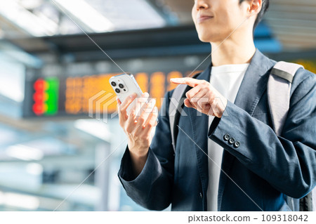 車站內拿著智慧型手機的中年男子。與京王電鐵合作拍攝。 車站內拿著智慧型手機的中年男子。與京王電鐵合作拍攝。 109318042
