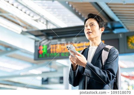 Middle-aged man looking at his smartphone at the station Photography provided by Keio Electric Railway Co., Ltd. 109318070