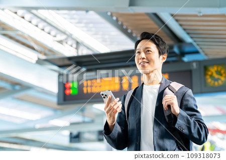 Middle-aged man looking at his smartphone at the station Photography provided by Keio Electric Railway Co., Ltd. 109318073