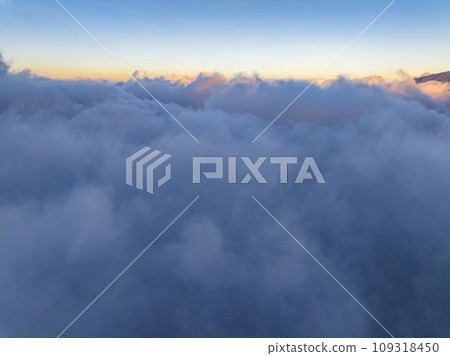 Aerial view of flowing fog waves on mountain tropical rainforest,Bird eye view image over the clouds Amazing nature background with clouds and mountain peaks in indonesia Aerial view of flowing fog waves on mountain tropical rainforest,Bird eye view image over the clouds Amazing nature background with clouds and mountain peaks in indonesia 109318450