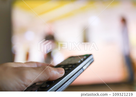 Hand turning on the TV with the remote control 109321219