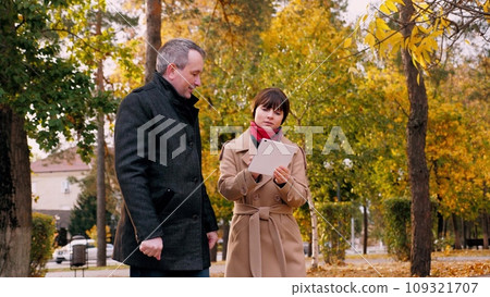 Female worker and male boss discuss company business during meeting in town park Female worker and male boss discuss company business during meeting in town park 109321707