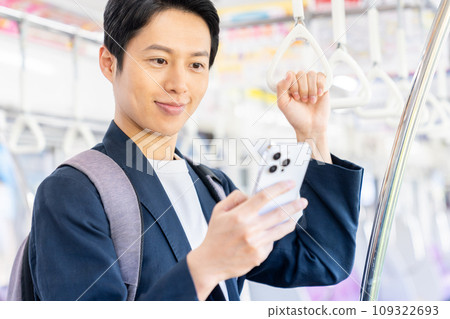 A businessman in office casual clothes on a commuter train. Photography provided by Keio Electric Railway Co., Ltd. 109322693