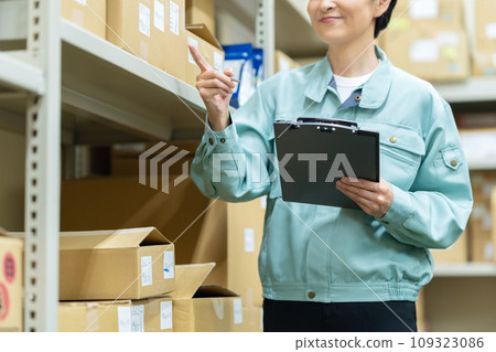 A middle-aged female worker inspecting items at a warehouse A middle-aged female worker inspecting items at a warehouse 109323086