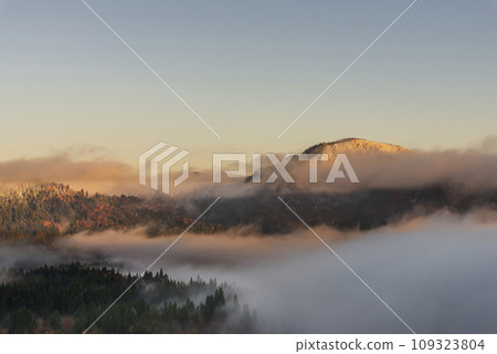 A sea of clouds bathed in the morning sun and mountains changing from autumn to winter 109323804