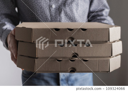 Caucasian male hands hold three pizza boxes side view with copy-space 109324066