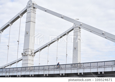 Man riding on bicycle across the bridge in the city. Man riding on bicycle across the bridge in the city. 109324671