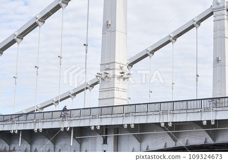 Man riding on bicycle across the bridge in the city. Man riding on bicycle across the bridge in the city. 109324673
