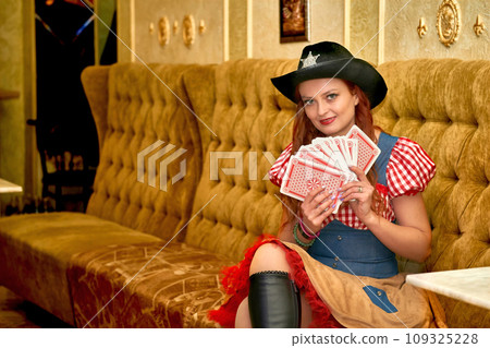 Young beautiful woman hosting a party in a cowboy costume with playing cards Young beautiful woman hosting a party in a cowboy costume with playing cards 109325228