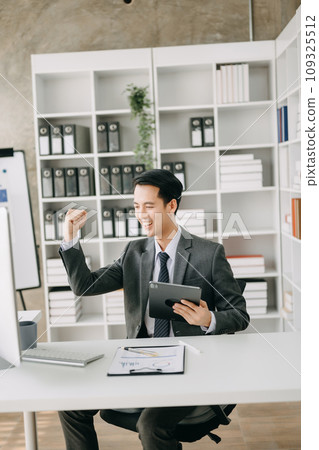 Asian business man are delighted and happy with the work they do on their tablet, laptop and taking notes at the office. Asian business man are delighted and happy with the work they do on their tablet, laptop and taking notes at the office. 109325512