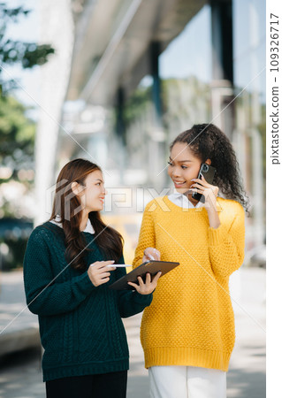 Asian Students are studying the campus park. Young people are spending time together. Reading book, working with laptop, tablet and communicating while sitting on stairs . 109326717