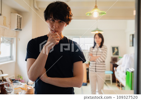 Husband being teased by his wife at home Husband being teased by his wife at home 109327520