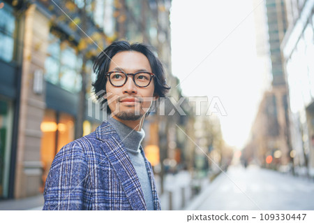 A man wearing a jacket walking down the street 109330447