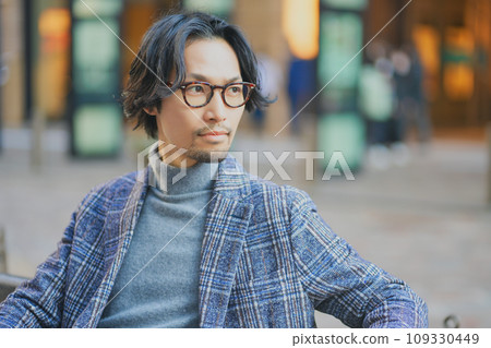 A man wearing a jacket sitting on a bench and taking a break A man wearing a jacket sitting on a bench and taking a break 109330449