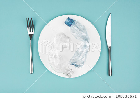 Bottle on the plate and other plastic waste on blue background 109330651
