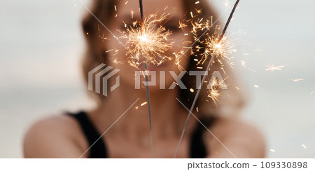 Beautiful woman with sparklers on the beach Beautiful woman with sparklers on the beach 109330898