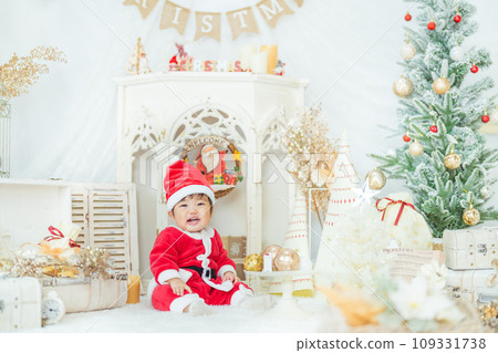 A smiling 1-year-old baby wearing a Santa costume and having fun at a Christmas tree photo set A smiling 1-year-old baby wearing a Santa costume and having fun at a Christmas tree photo set 109331738