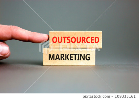 Outsourced marketing symbol. Concept words Outsourced marketing on beautiful wooden blocks. Beautiful grey table grey background. Businessman hand. Business Outsourced marketing concept. Copy space. Outsourced marketing symbol. Concept words Outsourced marketing on beautiful wooden blocks. Beautiful grey table grey background. Businessman hand. Business Outsourced marketing concept. Copy space. 109333161