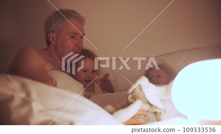 Dad tells a bedtime story to his little girls 109333536