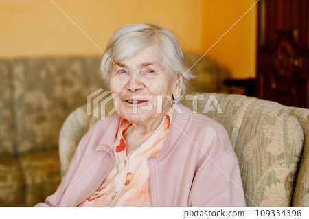 Senior woman of 90 years sitting at home. Portrait of old happy retired lady indoors 109334396