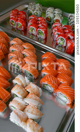 Sushi and rolls with caviar, shrimp and tuna, avocado on a gray background. Sushi and rolls with caviar, shrimp and tuna, avocado on a gray background. 109334860