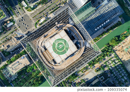 Helipad on the rooftop of the modern skyscraper. Glass business offices district. Aerial drone view of helipad on the roof of a skyscraper in downtown. Helipad on the rooftop of the modern skyscraper. Glass business offices district. Aerial drone view of helipad on the roof of a skyscraper in downtown. 109335074