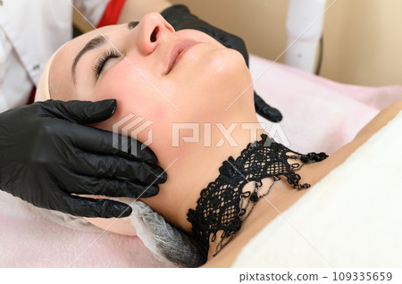 A beautician gives a relaxing face massage to a girl. 109335659
