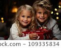 Happy little kids with a festive red and white Christmas gift 109335834