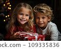 Happy little kids with a festive red and white Christmas gift 109335836