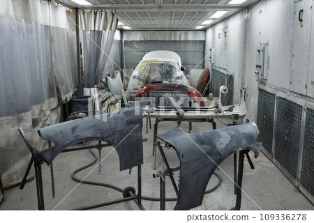 The photograph captures the scene of an automotive workshop, showcasing the process of painting various car parts. Different components of the vehicle car bonnet, bumpers, smaller details. The photograph captures the scene of an automotive workshop, showcasing the process of painting various car parts. Different components of the vehicle car bonnet, bumpers, smaller details. 109336278