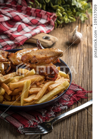 Baked chicken wings with french fries. 109337009