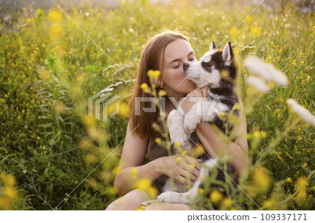 Beautiful young caucasian woman is playing with her puppy dog outdoor. 109337171