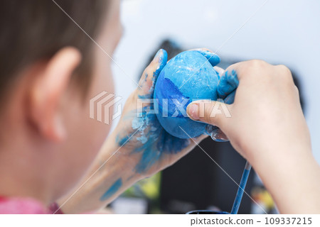 Kid is dyeing Easter eggs 109337215
