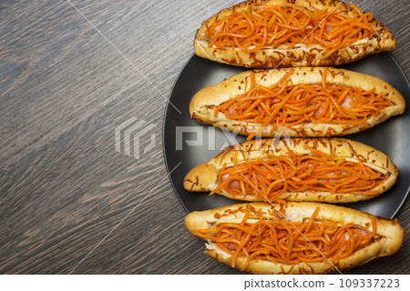 Tasty hot dogs on a black plate on a wooden background. Top view, copy space 109337223