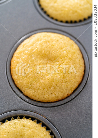 Cooling freshly baked lemon cupcakes on a kitchen counter. 109338034