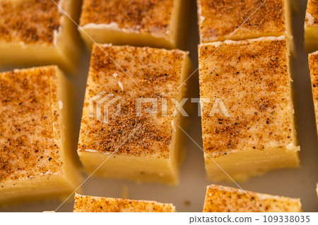 Homemade eggnog fudge pieces on a white cutting board. 109338035