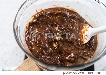 Melting chocolate chips and other ingredients in a glass mixing bowl over boiling water to prepare plain fudge. 109338049