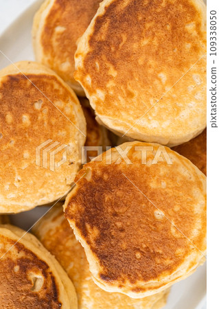 Freshly made eggnog pancakes on a white serving plate. Freshly made eggnog pancakes on a white serving plate. 109338050