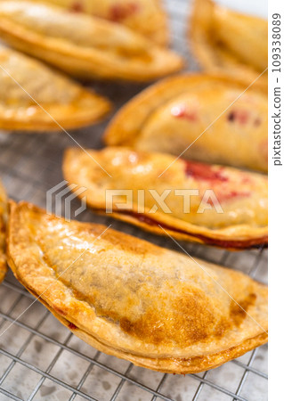Freshly baked sweet cherry empanadas in the air fryer on the kitchen counter. Freshly baked sweet cherry empanadas in the air fryer on the kitchen counter. 109338089