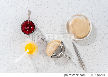 Flat lay. Filling empanada dough with cherry pie filling to make sweet cherry empanadas in the air fryer. 109338201