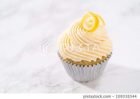 Lemon cupcakes with lemon buttercream frosting, and decorated with lemon swist. 109338344