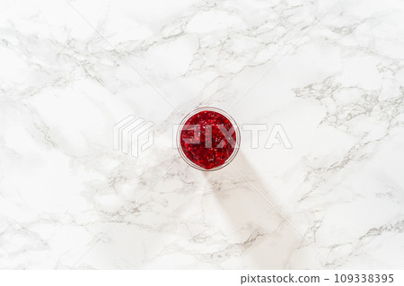 Flat lay. Freshly made Raspberry Cake Filling is carefully poured into a glass jar - ready to be used to add a burst of fruity flavor to any dessert. 109338395