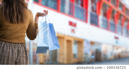 Happy beautiful young stylish woman with shopping bag while walking come out of mall on holiday Happy beautiful young stylish woman with shopping bag while walking come out of mall on holiday 109338725