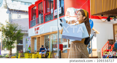 Happy beautiful young stylish woman with shopping bag while walking come out of mall on holiday 109338727