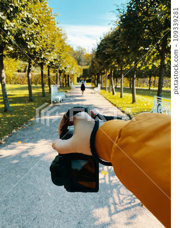 In a park, amidst trees, a man photographs a girl walking on a path, showcasing a first-person viewpoint. pov In a park, amidst trees, a man photographs a girl walking on a path, showcasing a first-person viewpoint. pov 109339281