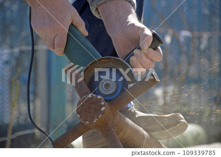male hands hold a working power tool for cutting metal male hands hold a working power tool for cutting metal 109339785
