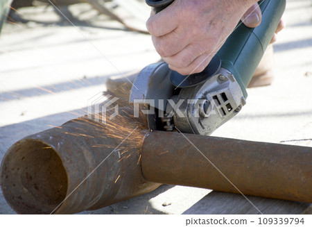 male hands hold a working power tool for cutting metal male hands hold a working power tool for cutting metal 109339794