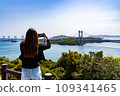 Rear view of a woman taking a picture of the Seto Ohashi Bridge from the Washuzan observation deck 109341465